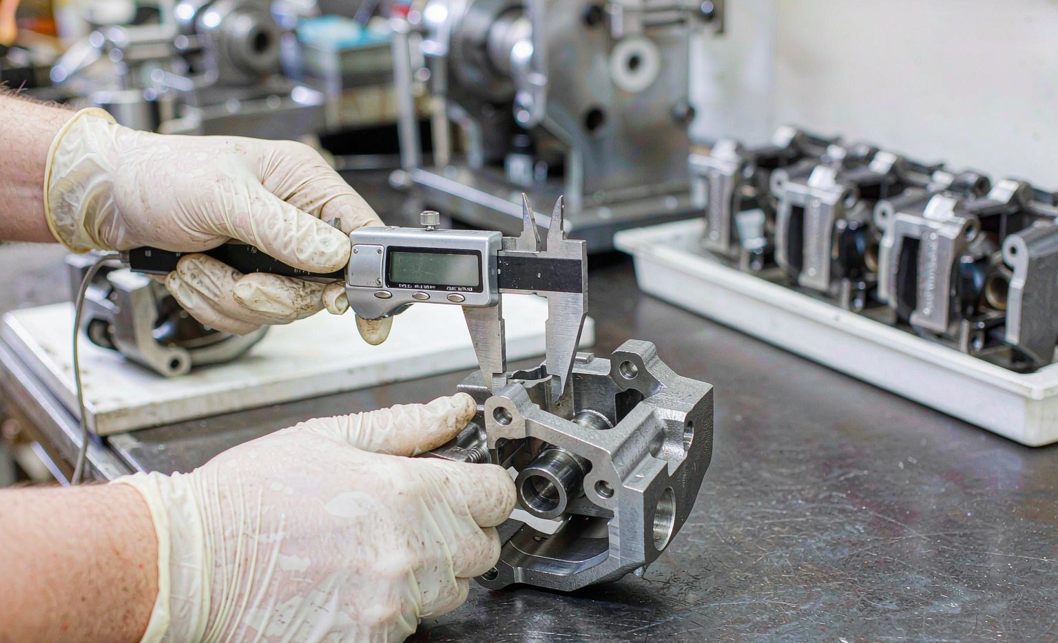 A brake caliper housing being measured with precision gauges during quality inspection at a machining plant