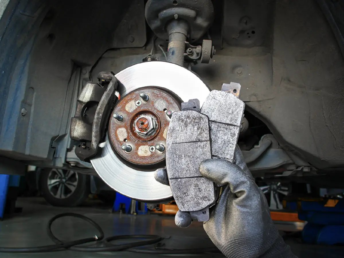 Professional mechanic installing Hyundai Kia brake pad set on vehicle — front disc brake assembly during service showing pad replacement procedure, real workshop conditions