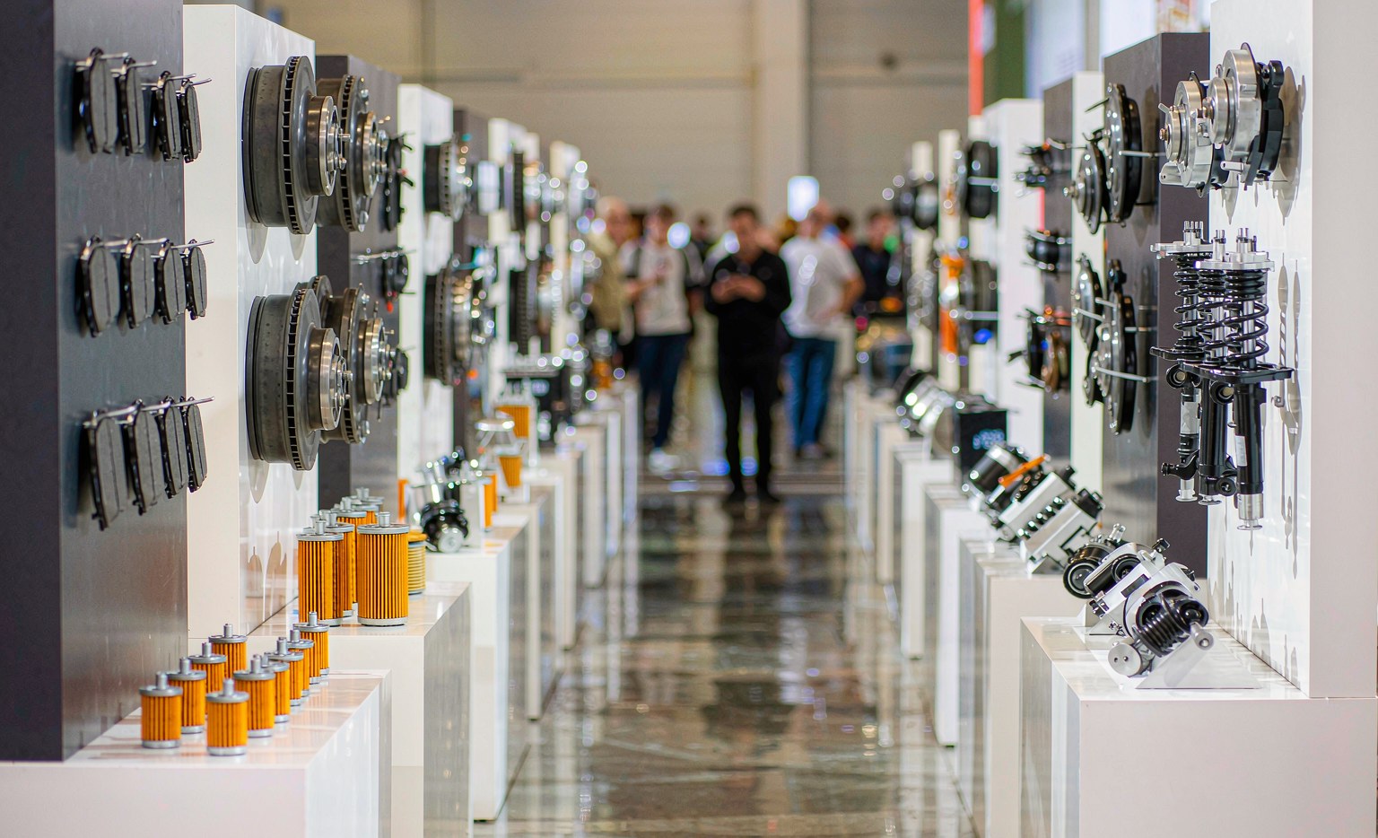 Exhibition aisle inside the Canton Fair auto parts halls with brake pads, filters and suspension components displayed on booth shelves