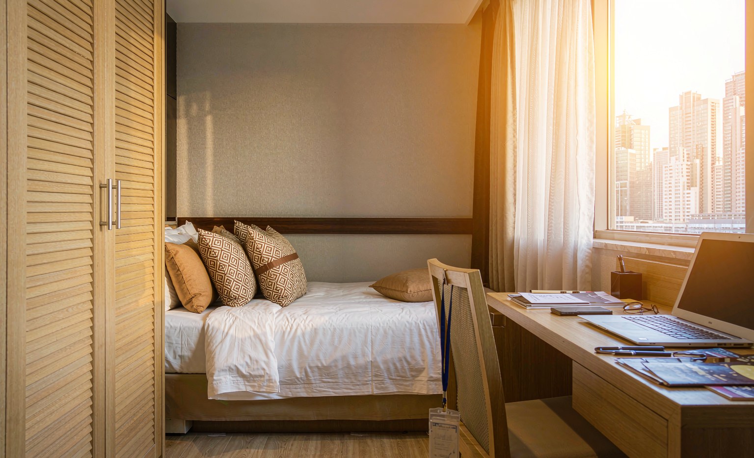 Business hotel room with a laptop, catalogues and a Canton Fair badge laid on the desk, window overlooking the Pazhou skyline in Guangzhou, illustrating guangzhou canton fair hotel choice