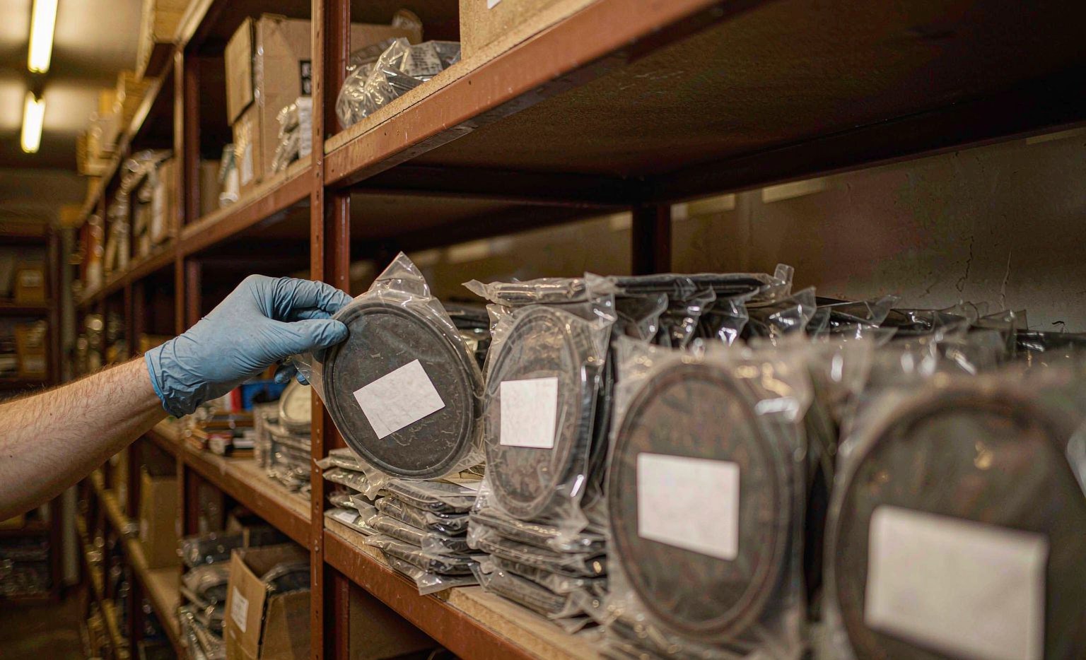 Poly-bagged valve cover gaskets and boxed gasket kits on warehouse shelves with OE number labels